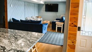 Una sala de estar moderna con un sofá, una mesa de centro y un televisor montado en la pared.