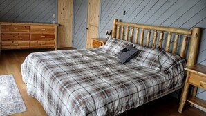 Un dormitorio con cama, cabecera de madera y cómoda.