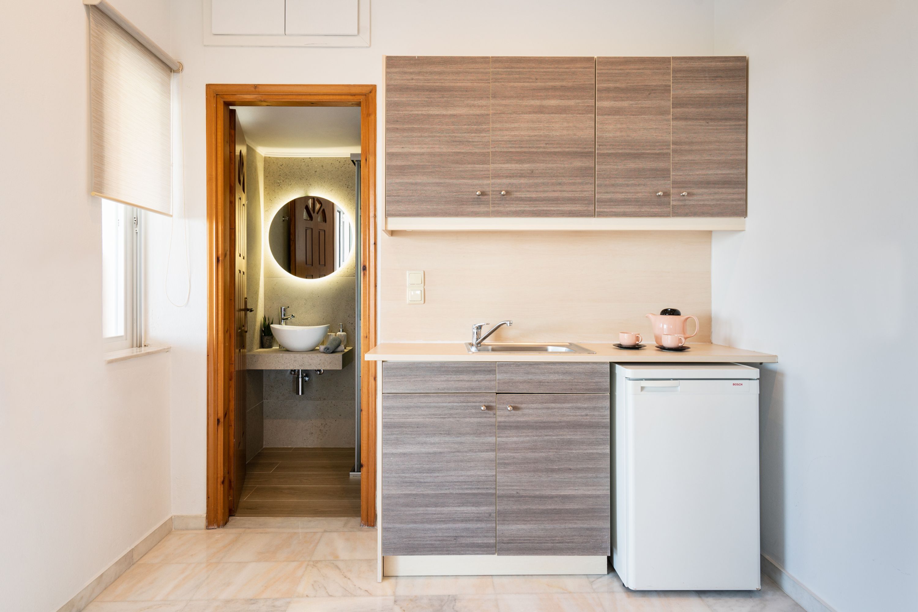 A compact kitchen with a sink, a small refrigerator, and wooden cabinets.