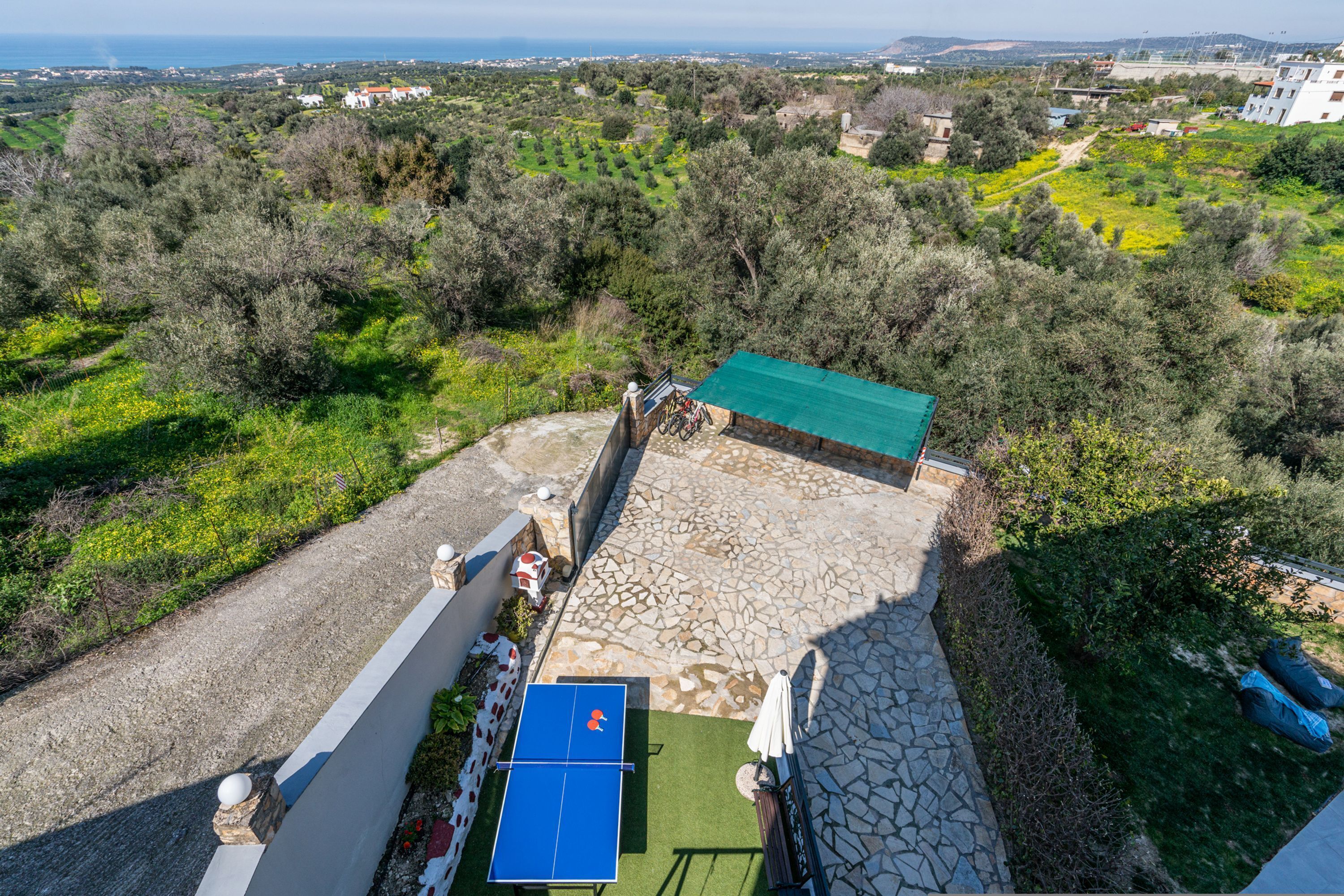 A rooftop terrace with a ping pong table, stone flooring, and a view of the surrounding countryside.