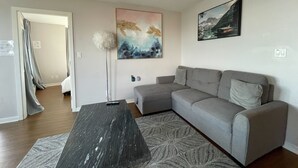 Una sala de estar moderna con un sofá gris, una mesa de centro negra y un cuadro abstracto grande en la pared.