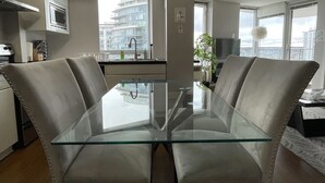 Una cocina moderna con una mesa de comedor de vidrio, electrodomésticos de acero inoxidable y vistas a un paisaje urbano.
