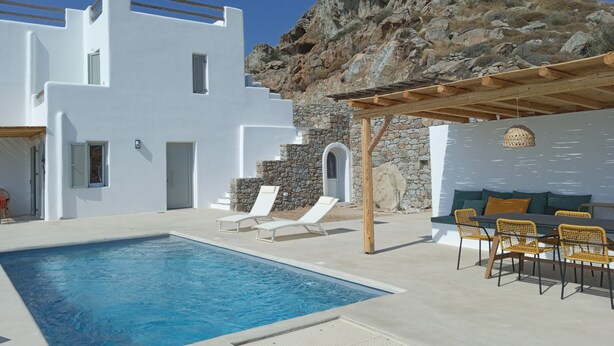 A pool area with a white building, a rock formation, and outdoor seating. - VILLA THEROS, 6 persons, swimming pool. Exceptional view! (NAXOS)
