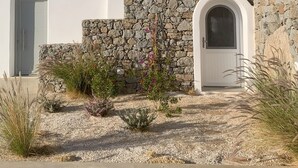 A white building with a stone wall entrance, a door, and a window with shutters. - VILLA THEROS, 6 persons, swimming pool. Exceptional view! (NAXOS)