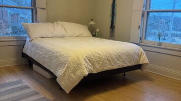 A bedroom with a bed, a nightstand, a lamp, and a window.