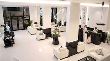 Un hall d’hôtel moderne avec des canapés blancs, un comptoir d’accueil et un espace de réception.