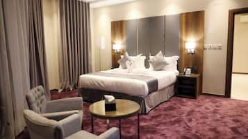 Una habitación de hotel con una cama grande, dos mesitas de noche, una silla y una mesa redonda pequeña.