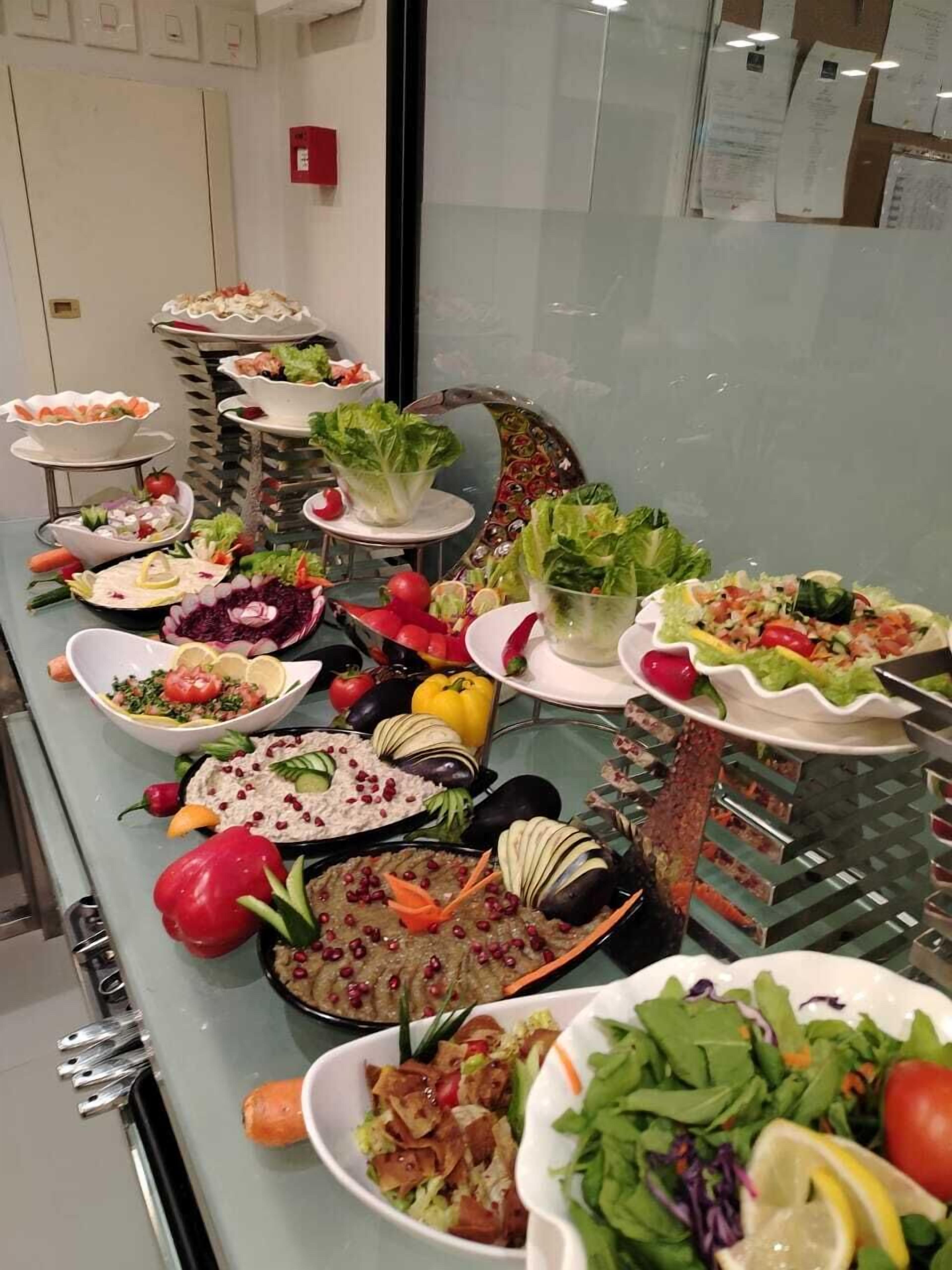 Un bufé con diversos platos, incluyendo ensaladas, verduras y salsas.