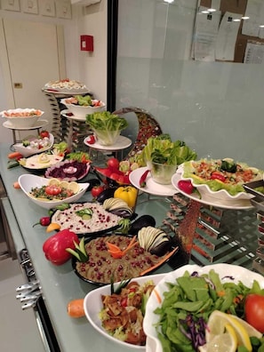 Ein Buffet mit verschiedenen Speisen, darunter Salate, Gemüse und Dips.