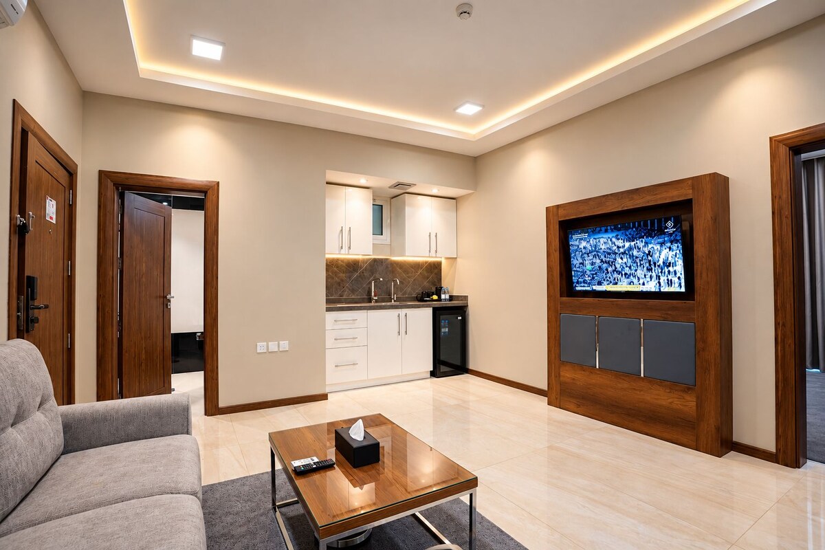 Una sala de estar moderna con un sofá, una mesa de centro, un televisor y una cocina al fondo.
