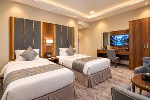 A hotel room with two beds, a desk, a chair, a television, and a wardrobe. - Golden Season Hotel - AR Rass (Ar Rass)