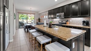 A modern kitchen with dark cabinets, a granite countertop, and stainless steel appliances.