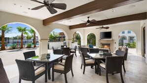 An outdoor patio with wicker furniture, a TV, and a fireplace.