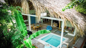 A poolside area with a thatched roof, a dining area, and a lounge with a view of the pool. - A natural setting in Playa Grande, peaceful and relaxing place! (Playa Grande)