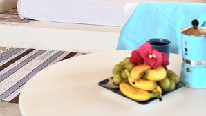 A bedroom with a bed, a nightstand, a lamp, a window with a view of trees, and a table with fruit and a container. - A natural setting in Playa Grande, peaceful and relaxing place! (Playa Grande)