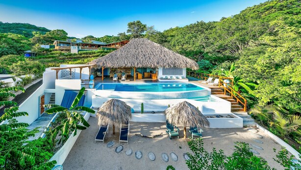 A resort with a pool, thatched-roof structures, and lush greenery. - A natural setting in Playa Grande, peaceful and relaxing place! (Playa Grande)