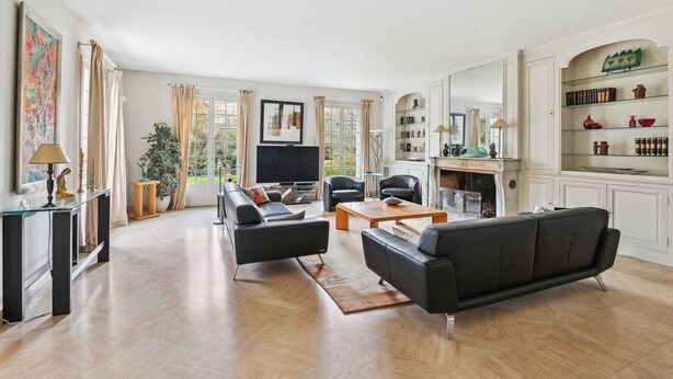 A spacious living room with a large TV, leather sofas, a coffee table, and a fireplace.