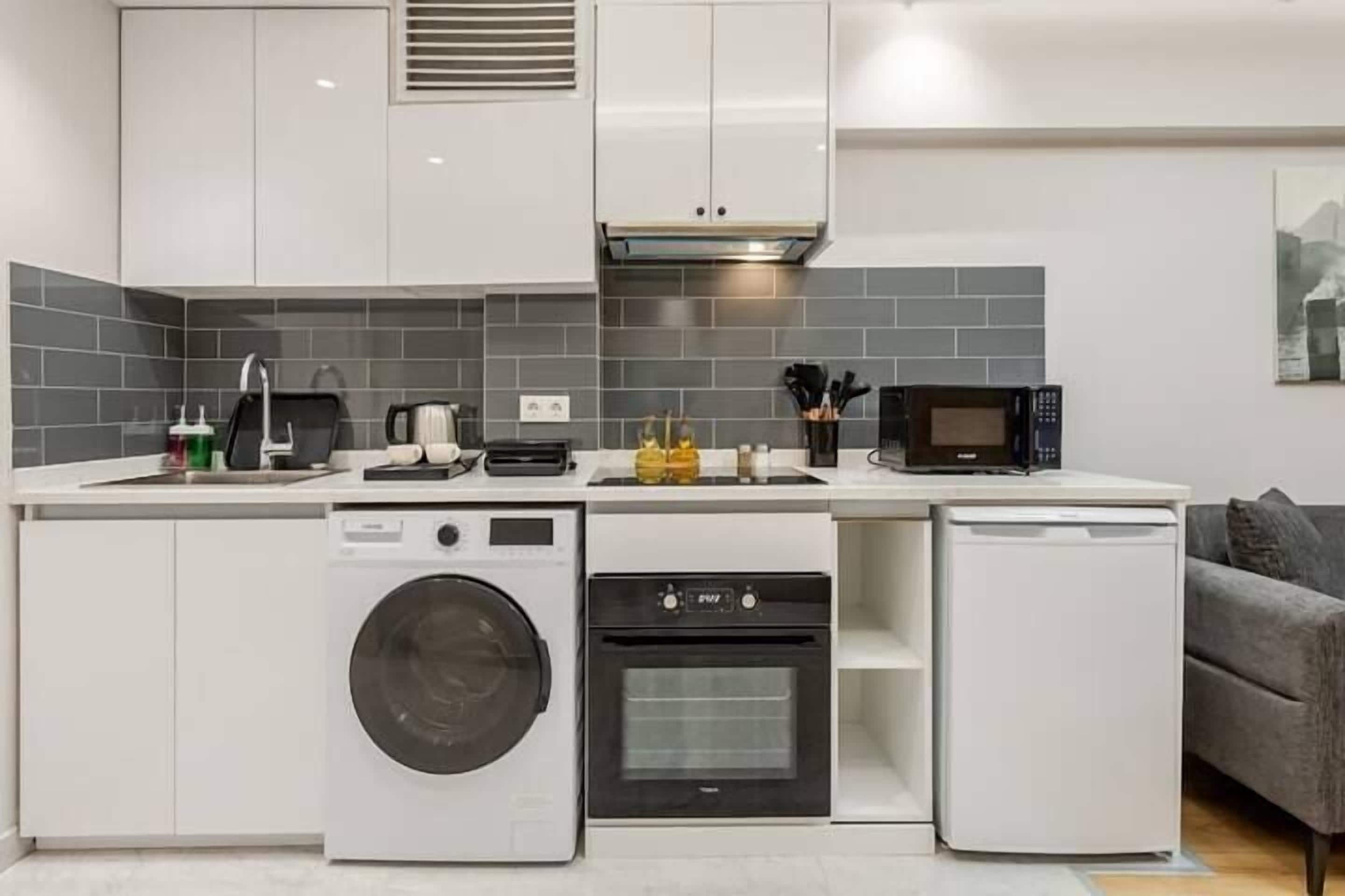 A compact kitchen with a washing machine, oven, microwave, and dishwasher.