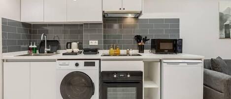 A compact kitchen with a washing machine, oven, microwave, and dishwasher.