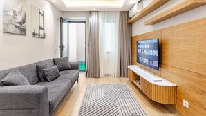 Una sala de estar moderna con un sofá gris, un mueble de entretenimiento de madera y un televisor de pantalla plana grande.
