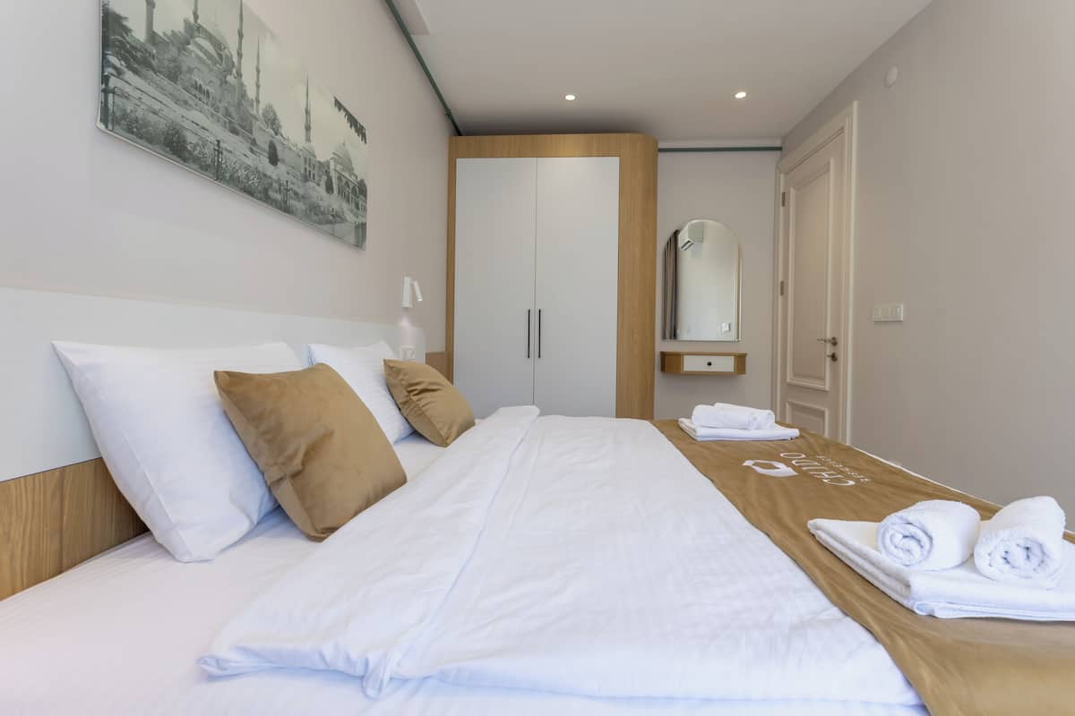 A hotel room with a large bed, a wooden headboard, a wall-mounted mirror, and a door.