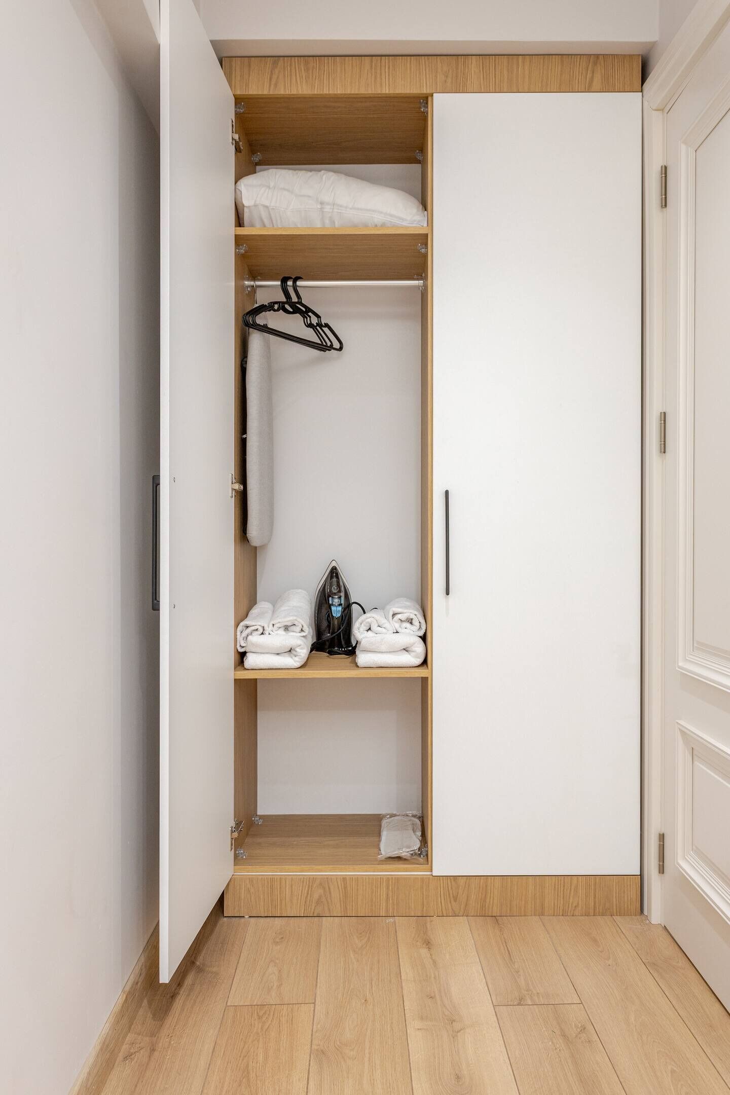 Un dressing avec des étagères en bois, une tringle à vêtements et des serviettes soigneusement pliées.