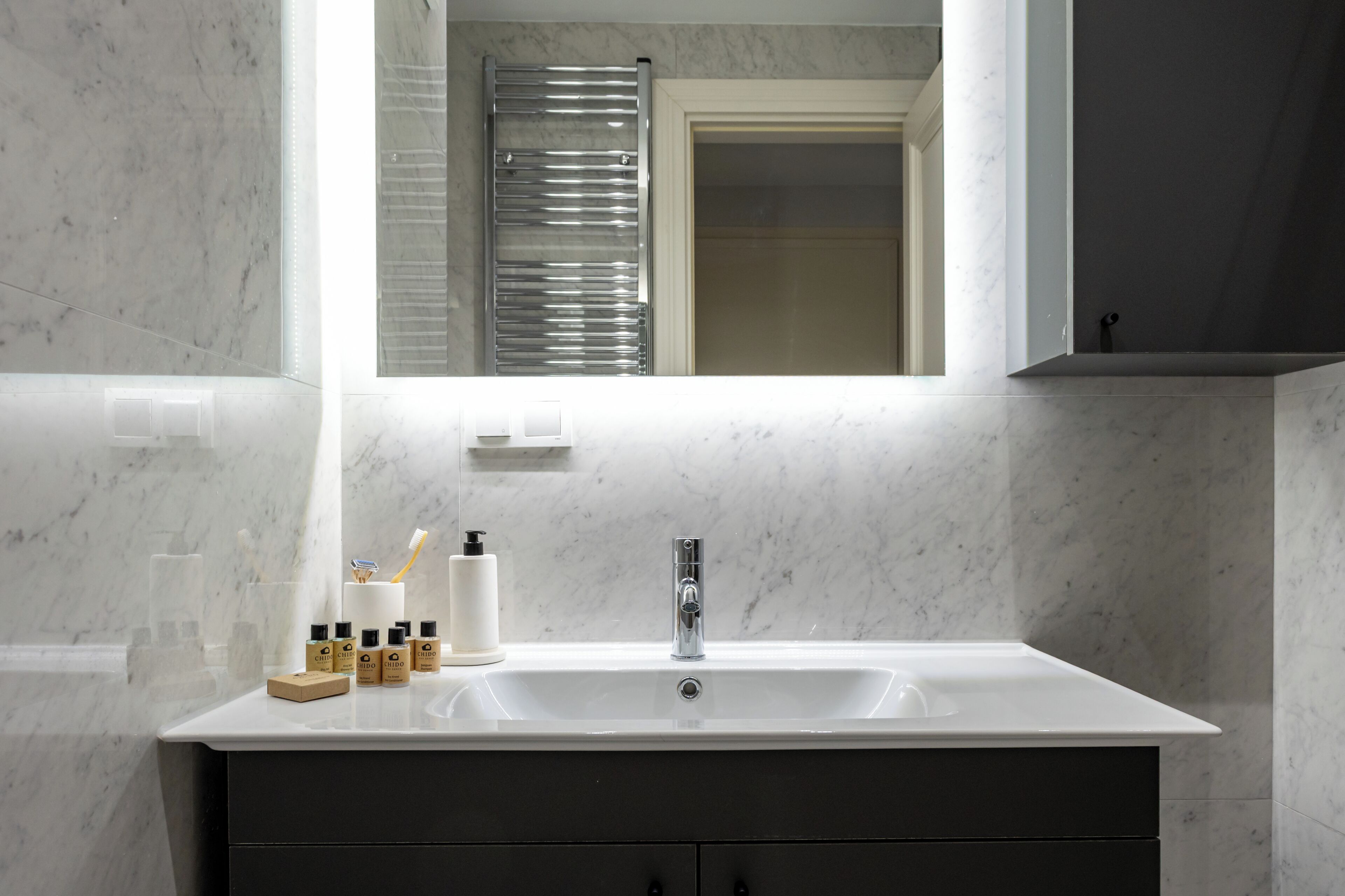 Un baño con un lavabo blanco, un espejo y artículos de aseo.