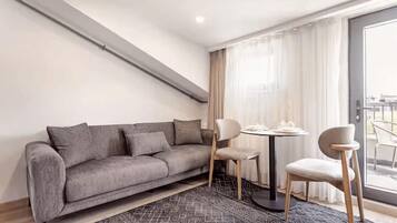 A modern living room with a grey sofa, two chairs, a small round table, and a patterned rug.