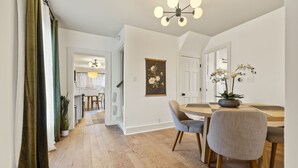 A modern dining area with a wooden table, chairs, and a chandelier. - Abode 81 in Newark (Newark)