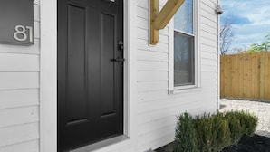 A house with a black front door, a number '81' sign, a small porch with steps, and a wooden beam structure above the door. - Abode 81 in Newark (Newark)