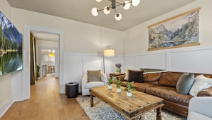 A living room with a wooden coffee table, leather sofa, and a painting on the wall. - Abode 81 in Newark (Newark)