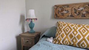 Un dormitorio con cama, una mesita de noche con lámpara y un adorno en la pared.