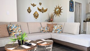 Una sala de estar moderna con un sofá seccional, un cuadro decorativo y una mesa de centro con una planta.