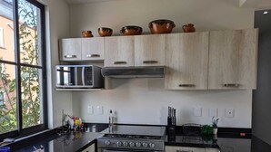 Una cocina moderna con estufa a gas, horno, microondas y muebles de madera.
