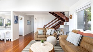 A spacious living room with a wooden staircase, a dining area, and a kitchen.