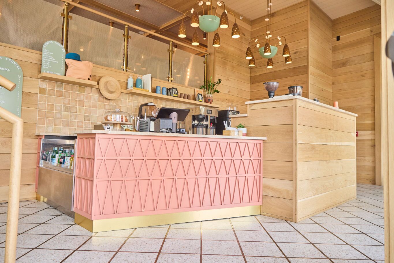Una cocina moderna con paredes de madera, una encimera rosa y diversos electrodomésticos.