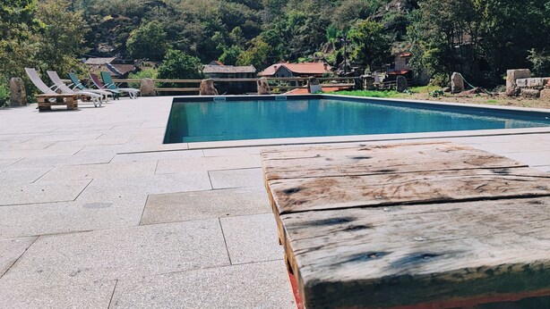 A swimming pool with lounge chairs and a wooden deck. - Aldeia de Pontes (Melgaco)