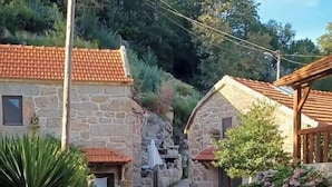A narrow cobblestone street flanked by stone buildings with tiled roofs. - Aldeia de Pontes (Melgaco)