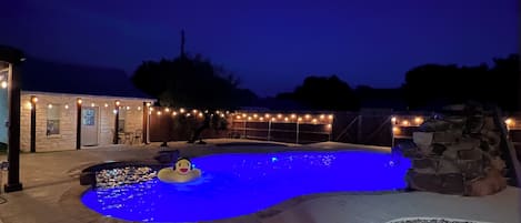 Ein Swimmingpool mit einer Enten-Schwimmfigur, umgeben von einer Steinmauer und einem Holzboden.
