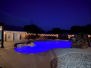 A swimming pool with a duck float, surrounded by a stone wall and a wooden deck.