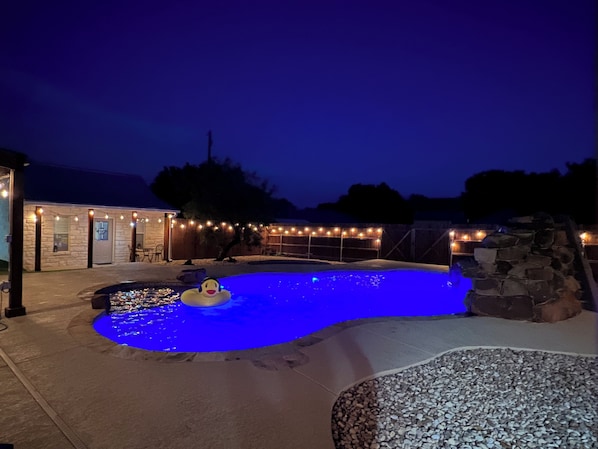 A swimming pool with a duck float, surrounded by a stone wall and a wooden deck.
