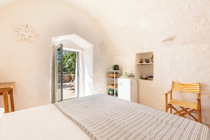 A bedroom with a bed, a wooden chair, a white wardrobe, and a small table. - 5 km from the beaches of Pescoluse, charming trullo in the countryside in Salve (Salve)
