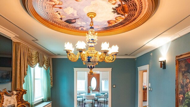 Een ruime woonkamer met een weelderige kroonluchter, een ronde marmeren salontafel en een grote bank.