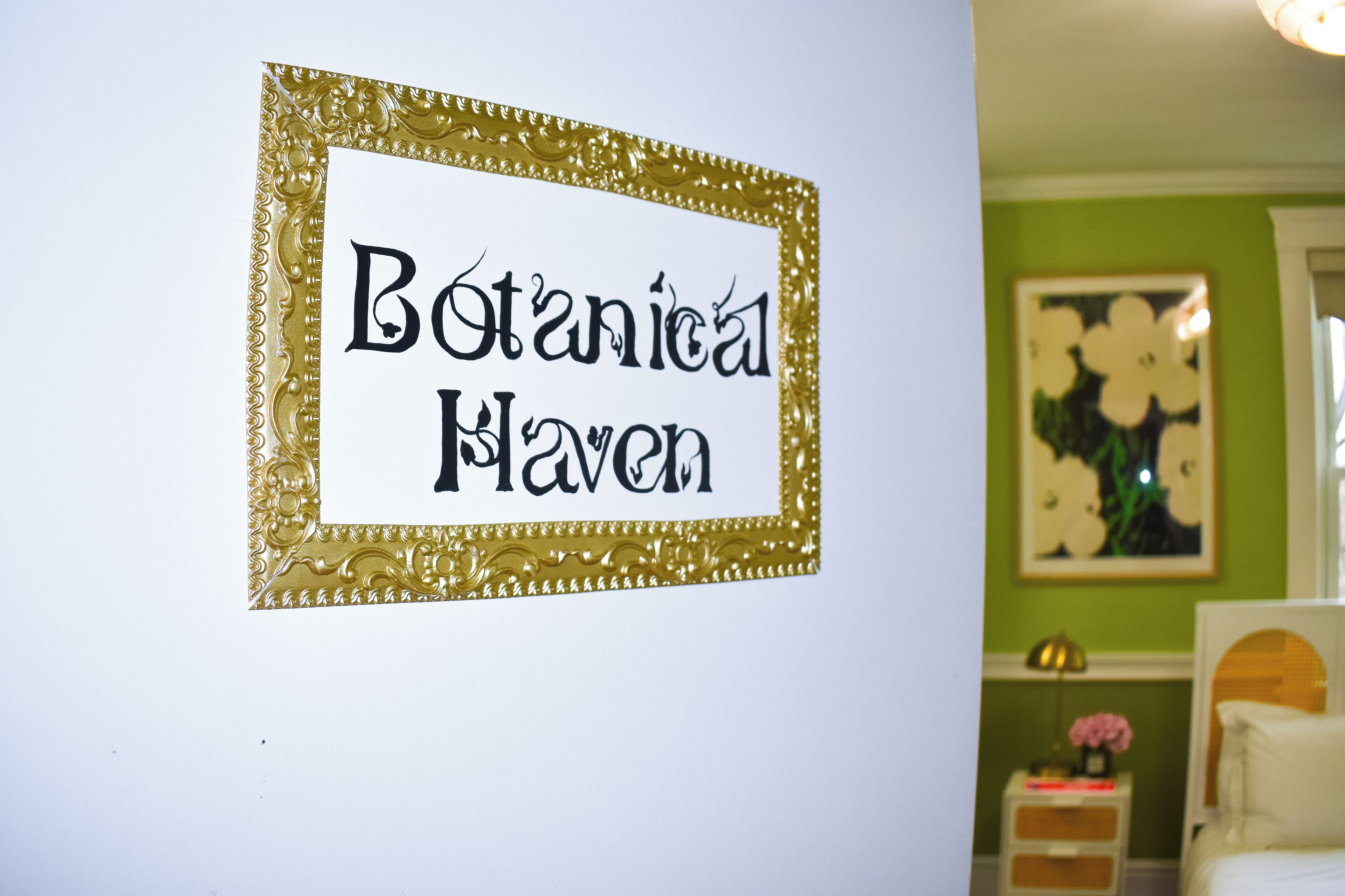 Un cartel en marco con el texto 'Botanical Haven' sobre una pared blanca.
