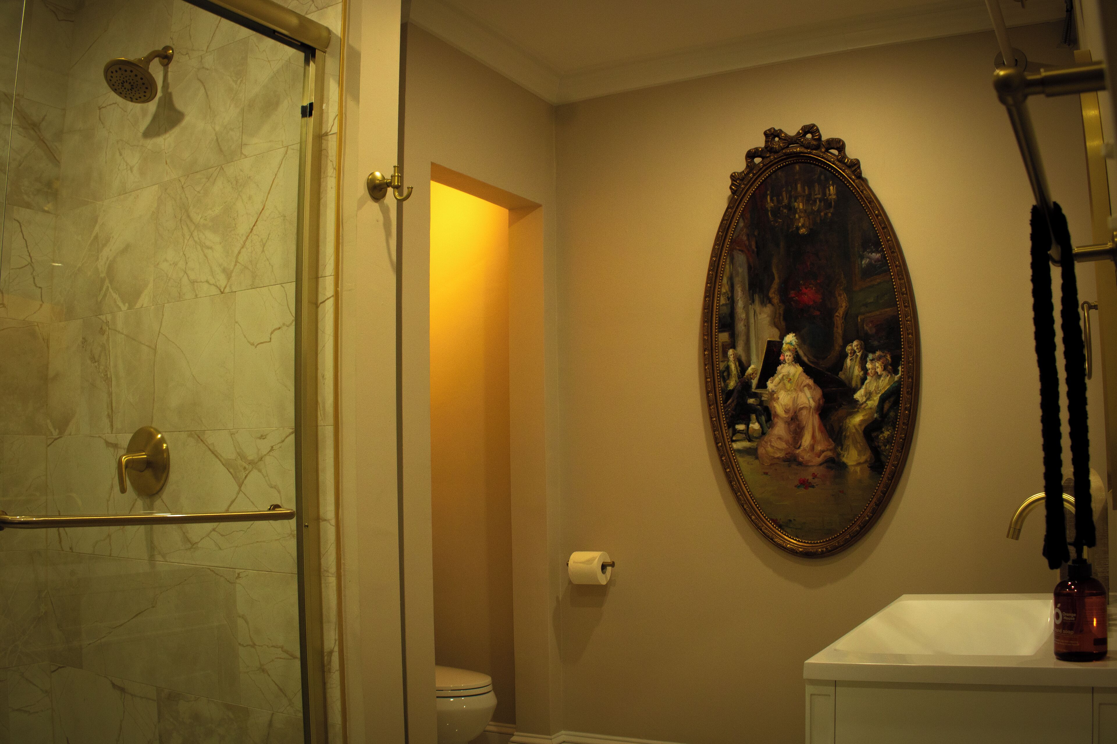 Un baño con ducha, inodoro, lavabo y un cuadro en la pared.