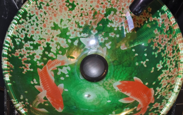 Un tazón de vidrio verde con peces koi y un centro negro.