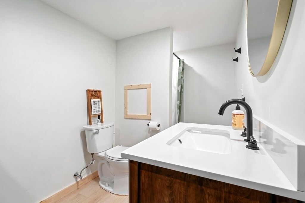 A modern bathroom with a white sink, black faucet, and a wooden cabinet.
