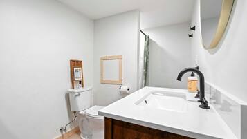 A modern bathroom with a white sink, black faucet, and a wooden cabinet.