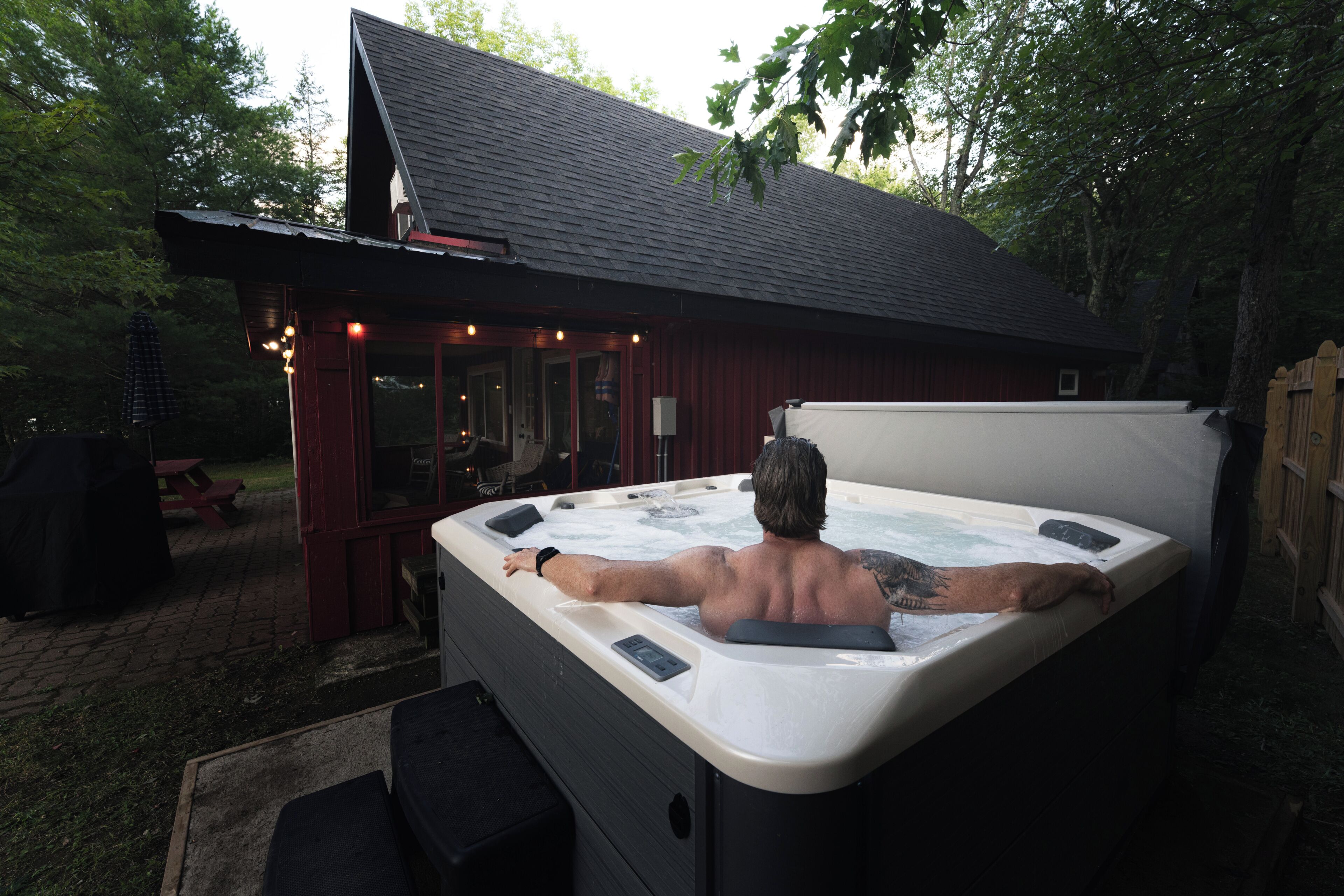 Een bubbelbad in een achtertuin met een houten terras en een overdekte patio.