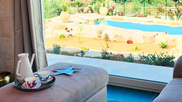 Ein Zimmer mit Blick auf einen Pool, Grünflächen und eine ferne Stadt.